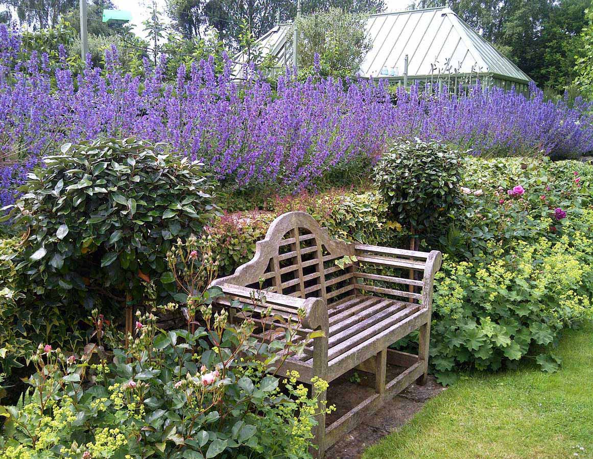 Classic garden bench inset into border with bay trees. Rae Wilkinson Garden and Landscape Design Surrey, Sussex, Hampshire, London, South-East England