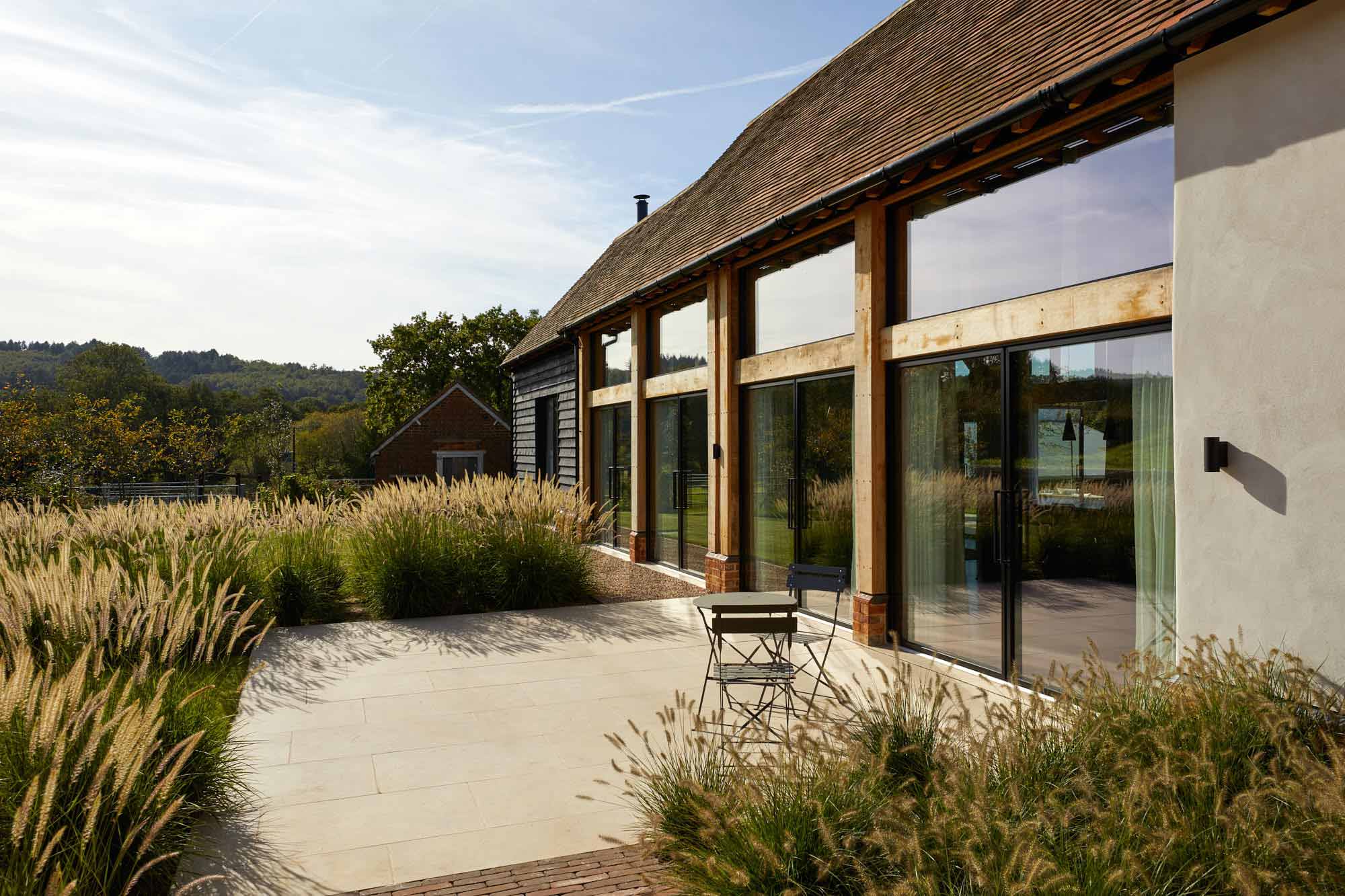 Meadow planting against black barn. Rae Wilkinson Garden and Landscape Designer Surrey, Sussex, Hampshire, London, South-East England